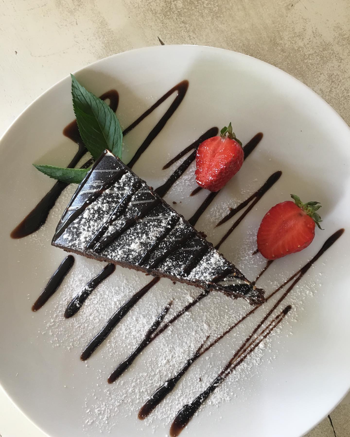 Eleganckie ciasto czekoladowe z sosem, truskawkami i cukrem pudrem